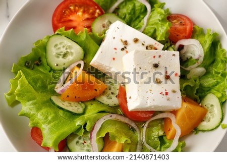 Delicious greek salad with vegetable and feta cheese, close up. Pepper on cheese.