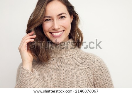 Portrait of a happy smiling brunette woman looking beautiful standing isolated on white background in a sweater. Young female girl with a perfect smile. Royalty-Free Stock Photo #2140876067