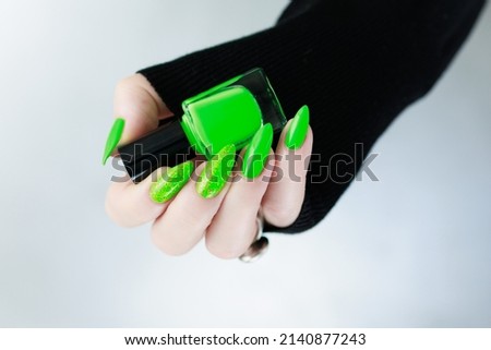 Female hand with white skin, with long nails and neon green nail polish