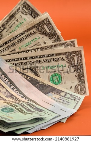 Dollar bills lying on an orange table. Photography in vertical format.