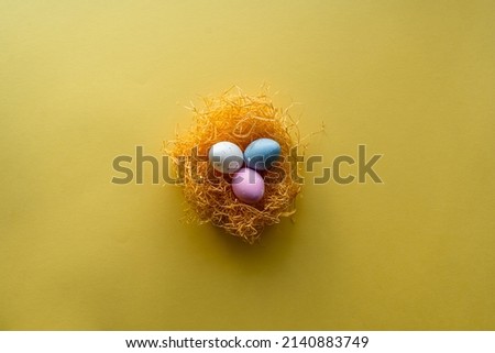  Nest with Easter eggs on yellow background with copy space for text. Royalty-Free Stock Photo #2140883749