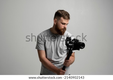 Bearder videographer filmmaker cinematographer dop with 3-axis gimbal and dslr camera. Filmmaking, videography, hobby and creativity concept. Royalty-Free Stock Photo #2140902143