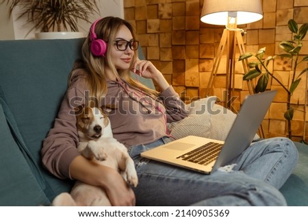 A girl with a dog watching a movie on a laptop with headphones. Pets and pet friends for people Royalty-Free Stock Photo #2140905369
