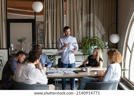 Confident business team leader speaking to employees at corporate meeting. Boss discussing sales reports, teamwork results with group. Coach, mentor, teacher training interns, office staff Royalty-Free Stock Photo #2140914771