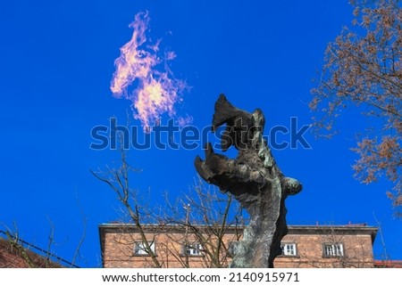 Wawel dragon spewing fire into the blue sky on a sunny day against the backdrop of the red brick wall of the castle