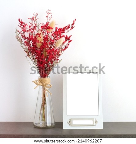 Flower bouquet in glass vase and blank white vintage wooden frame on table background with copy space , Banner for mock up, template