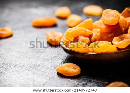 Delicious dried apricots in a wooden plate. On a black background. High quality photo