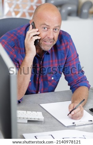 happy mature man on the phone working in a office Royalty-Free Stock Photo #2140978121