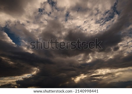 dark dramatic sky, bright sunlight and black silhouette of clouds as background