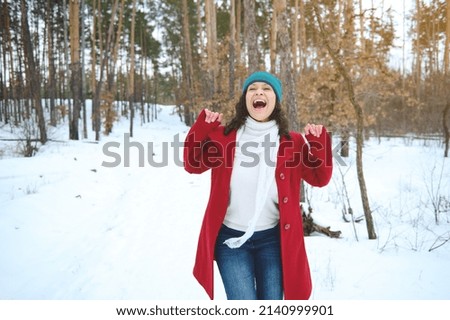 Winter holidays and travel concept. Outdoor recreation. Beautiful woman enjoys a beautiful sunny day while relaxing in a snowy nature. The sun's rays fall through the pine trees on a snowy forest path Royalty-Free Stock Photo #2140999901