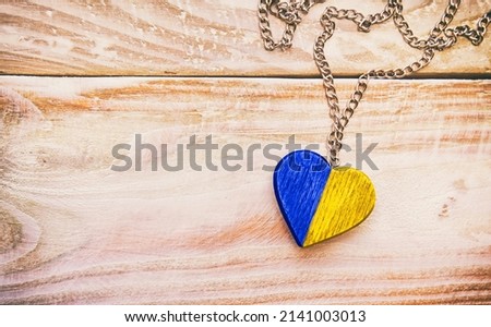 The wooden heart in colors of Ukrainian flag lying on the wooden table. 