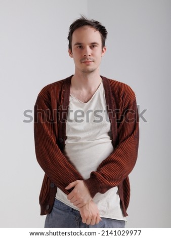 young caucasian man standing against a white isolated background. emotions of depression, anger, and frustration. A man in a cardigan with messy, disheveled hair. 
Portrait of one sad man  Royalty-Free Stock Photo #2141029977