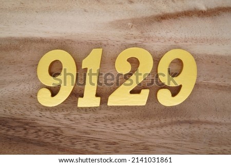 Wooden  numerals 9129 painted in gold on a dark brown and white patterned plank background.
