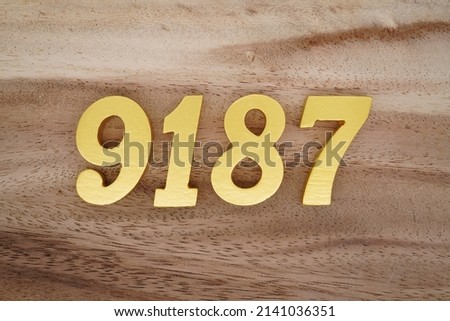 Wooden  numerals 9187 painted in gold on a dark brown and white patterned plank background.