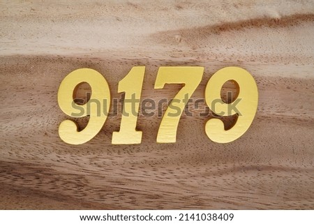 Wooden  numerals 9179 painted in gold on a dark brown and white patterned plank background.