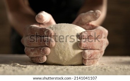 Cinematic close up of professional artisan baker chef is making with flour loaf of dough for preparation of pasta, pizza and other pastries in rustic bakery kitchen. Royalty-Free Stock Photo #2141041107