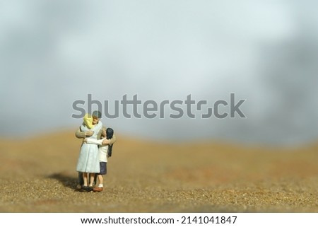 Miniature people toy figure photography. Family reunion concept. Father hugging his wife and daughter in the desert. Image photo