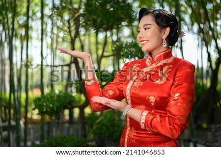 Portrait beautiful Asian woman in a Chinese cheongsam spreads her palm as blank space to insert picture for advertisement, copy space