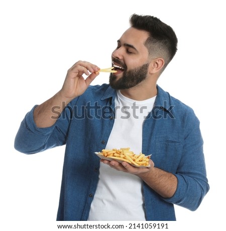 Young man eating French fries on white background Royalty-Free Stock Photo #2141059191