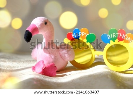 Baby pink toy flamingo and Happy Birthday glasses. Baby-room decor, interior of nursery bedroom. Baby shower or child birthday concept 
