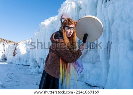 Red-haired girl dressed as a shaman on the ice of Lake Baikal