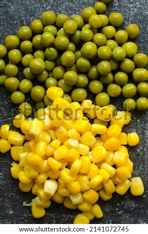 canned corn and green peas on a neutral background, close-up. Top view, vertical photo.