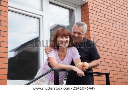 Elderly couple in casual clothes near  country house.