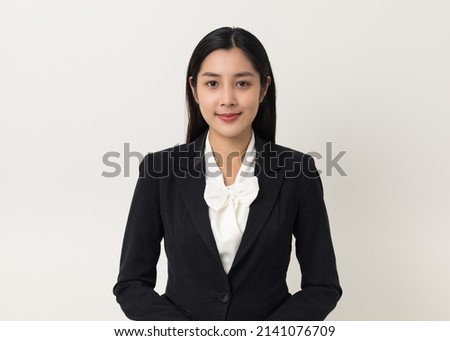 Young asian business woman smiling to camera standing pose on isolated white background. Female around 25 in suit portrait shot in studio. Royalty-Free Stock Photo #2141076709