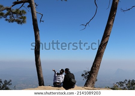 Romantic picture of a couple sitting and looking at the misty view at Phu Kradueng, Thailand.