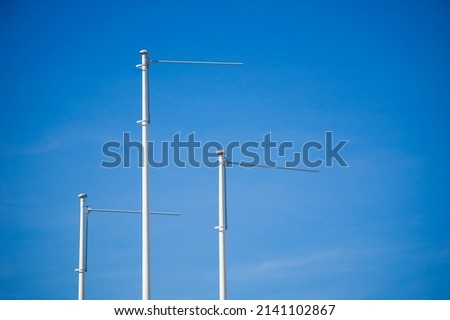 Triple empty flagpole against blue sky.