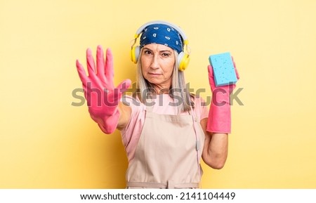 middle age pretty woman looking serious showing open palm making stop gesture. scourer cleaner