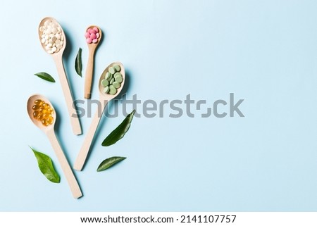 Top view Variety of vitamin and mineral pills in wooden spoon on Colored background. Top view of assorted pharmaceutical medicine pills. Dietary supplement healthcare product. Royalty-Free Stock Photo #2141107757