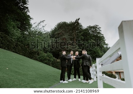 groom and his groomsmen friends in stylish suits drinking whiskey outdoor, morning before the wedding preparation, emotional group of friends celebrating Royalty-Free Stock Photo #2141108969