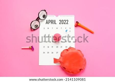 Calendar with marked date 1 APRIL and party decor on color background. April Fools Day celebration