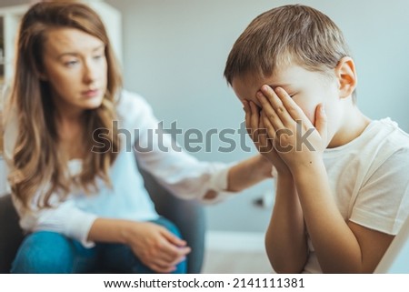 Children need help. Upset little boy crying in psychologist's office unable to control emotions, sharing problems and traumas, professional psychotherapist comforting kid, side view Royalty-Free Stock Photo #2141111381