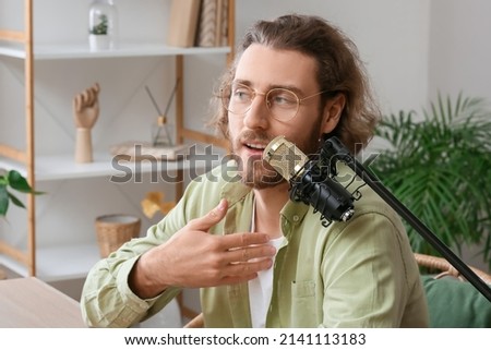 Male blogger using microphone at home