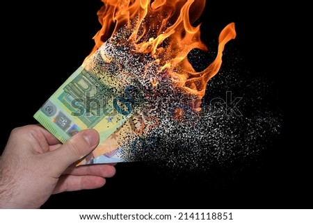 three burning euro bank notes held in one hand decomposes and dissolves due to inflation with black background Royalty-Free Stock Photo #2141118851