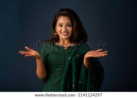 Portrait of a successful cheerful young girl holding and presenting something on hand with a happy smiling face.
