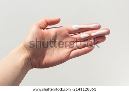 A person applying the correct amount of sunscreen for face and neck. Royalty-Free Stock Photo #2141128861