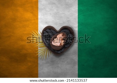 Newborn portrait in heart on background of national flag. Photography peace concept. Ivory Coast