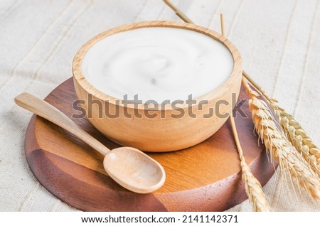 The Greek yogurt in a wooden bowl and dry barley on tablecloth.