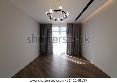 white room in the interior of the house with a large window, chandelier and floor