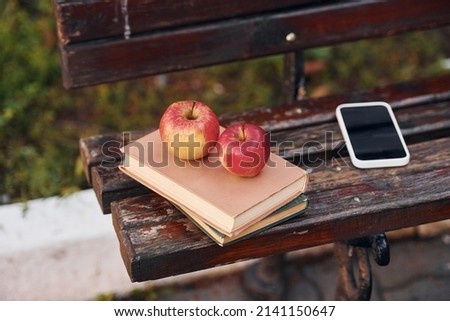 Close up view of couch, and books, apples and smartphone on it.