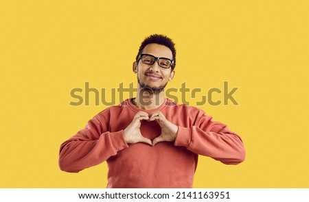 Come to me my love. Portrait of attractive african american man showing love gesture isolated on yellow background. Funny guy showing heart on camera. Valentine's day, romance and love concept.