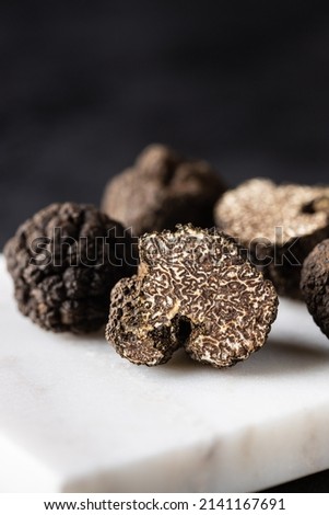 Brown truffles in a cut on a white marble board with a dark background. Truffle mushrooms on a cutting board. Culinary delight. Close up. Macro.  Royalty-Free Stock Photo #2141167691