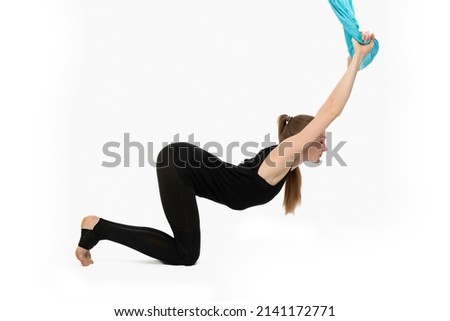 Girl does yoga and does flexibility exercise. Training with sports hammock. Side view. White background
