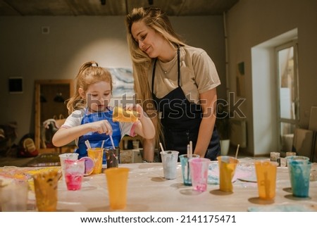 Mom and daughter painting a picture mixing paints