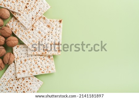 Passover celebration concept. Matzah, red kosher and walnut. Traditional ritual Jewish bread on light green monochrome background. Spring. Passover food. Pesach Jewish holiday.