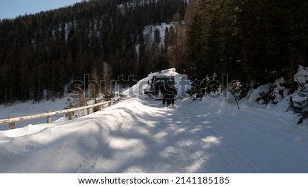 Snow groomer with skiers on the way through the forest 