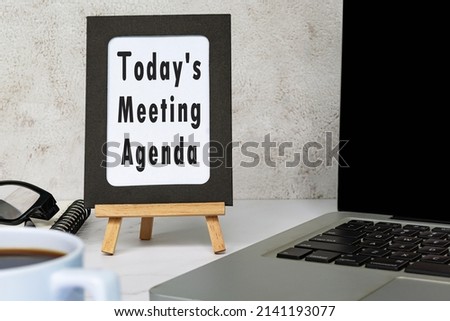 Today's meeting agenda text written on chalkboard with notebook on white desk. Meeting and goal concept. Royalty-Free Stock Photo #2141193077